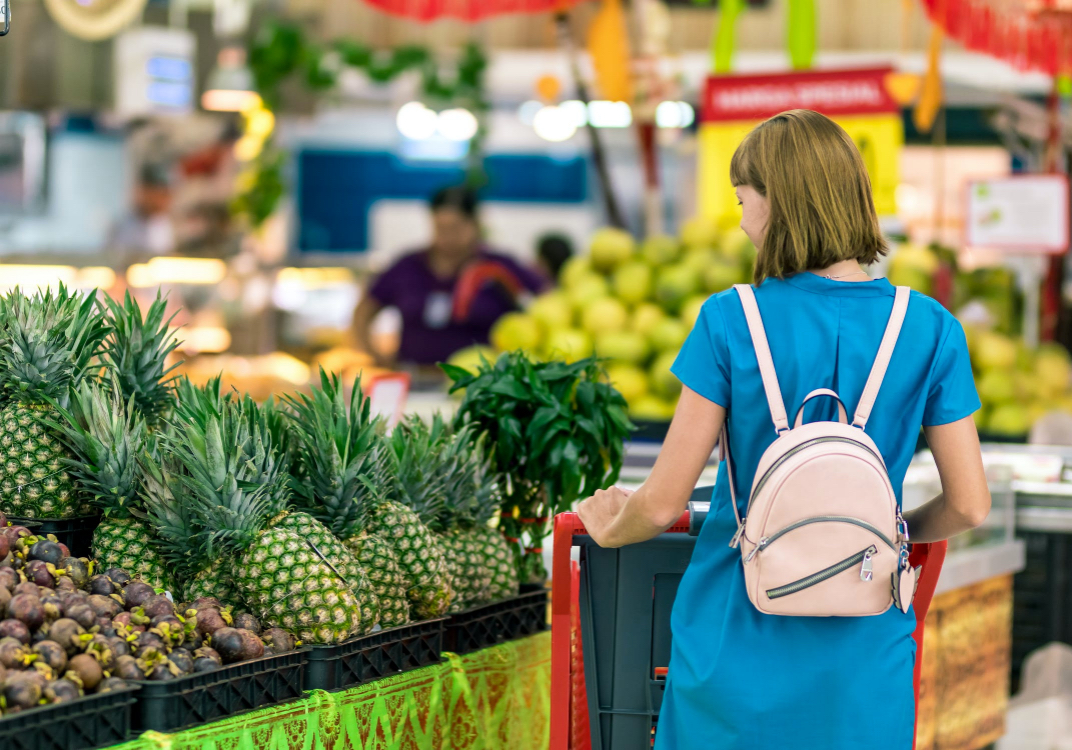 woman looking a pineapples at a grocery store